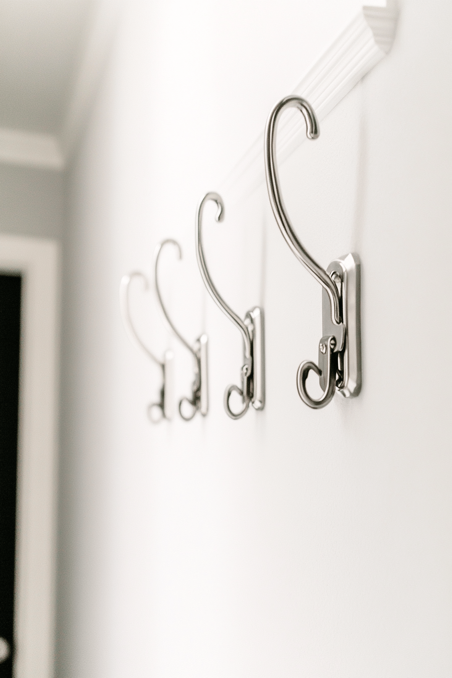 Mehrere elegante Wandhaken an einer weißen Wand im Flur.