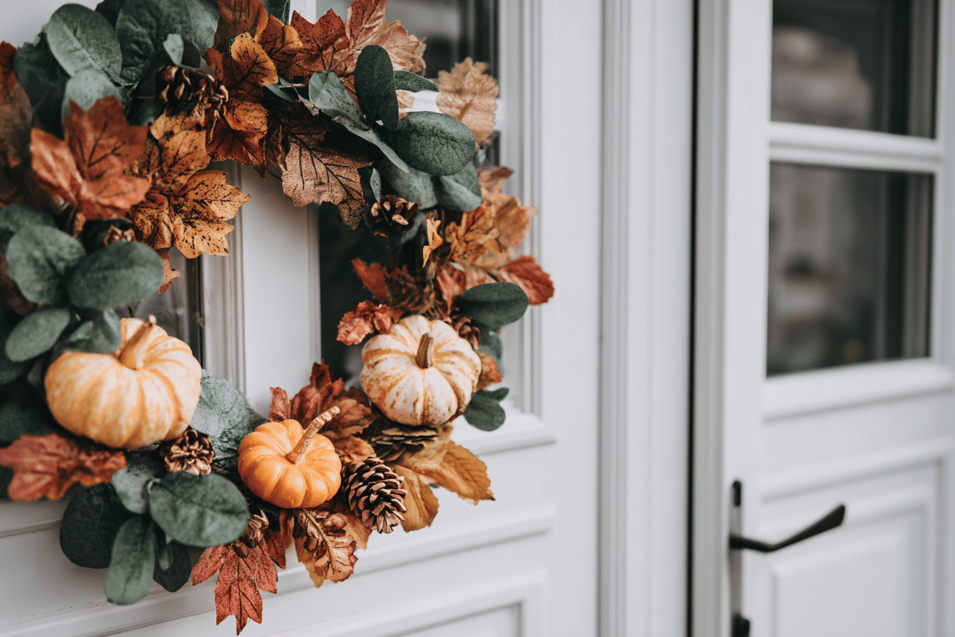Herbstkranz mit Kürbissen an weißer Tür