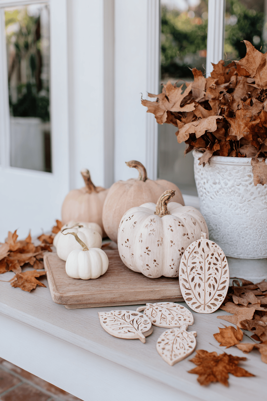 Herbstliche Gartendeko mit geschnitzten Kürbissen und getrockneten Blättern.