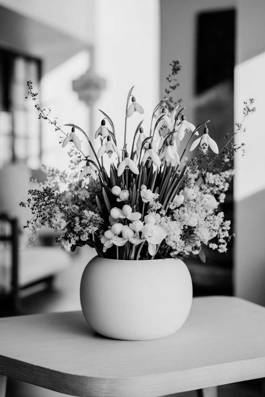 Ein Arrangement aus Schneeglöckchen und Winterblumen in einem weißen Keramiktopf