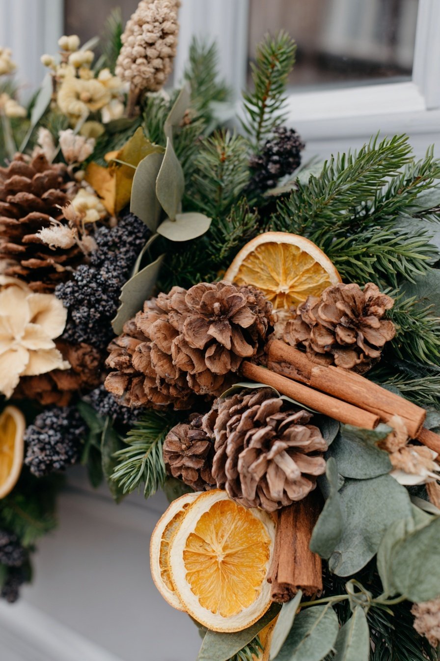 Nahaufnahme eines Türkranzes mit Tannenzweigen, Zapfen, getrockneten Orangenscheiben und Zimtstangen