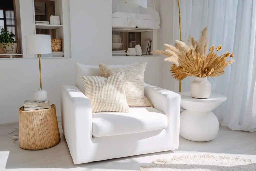 Weißer Sessel mit Kissen und Trockenblumen in modernem Wohnzimmer