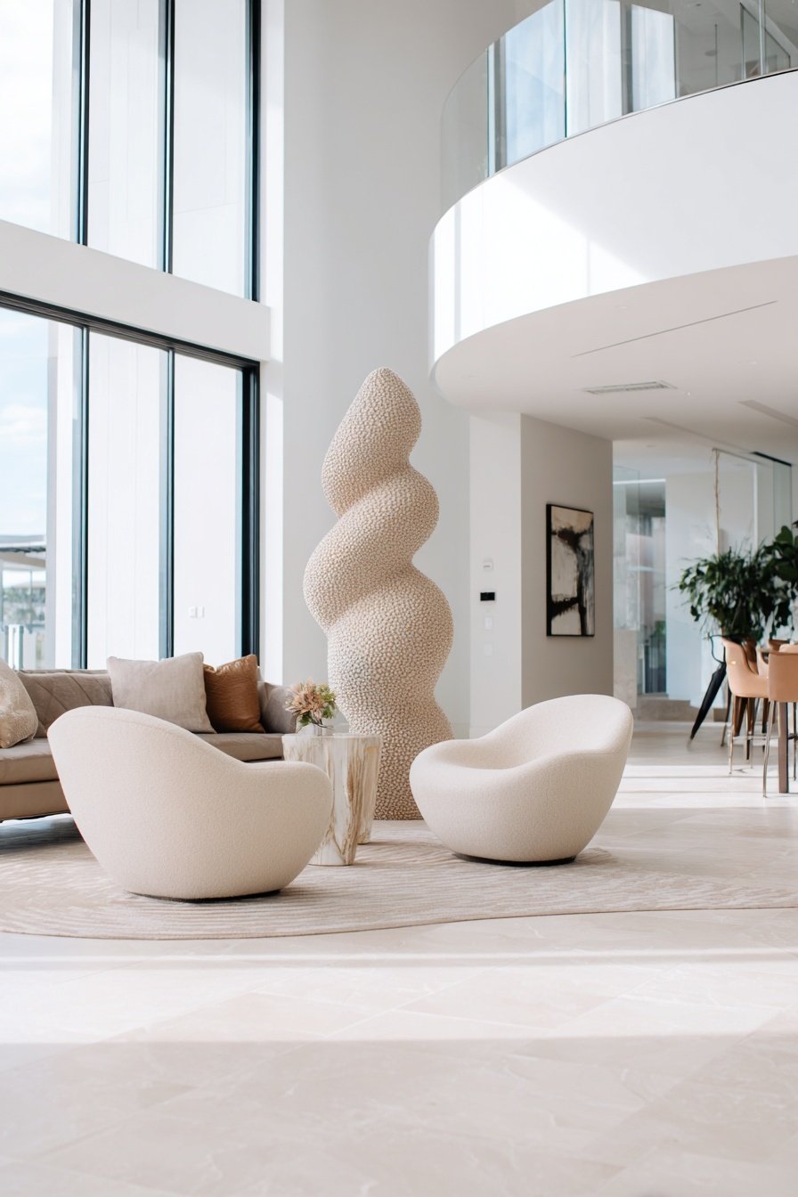 Helles Wohnzimmer mit Designmöbeln, runden Sesseln und einer geschwungenen Skulptur