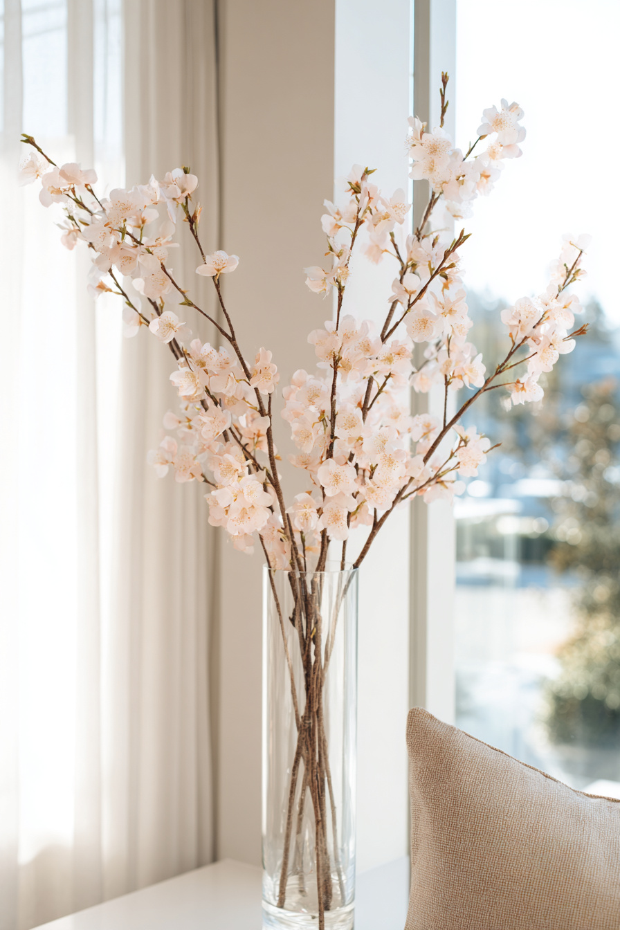 Kirschblütenzweige in klarer Glasvase auf Tisch