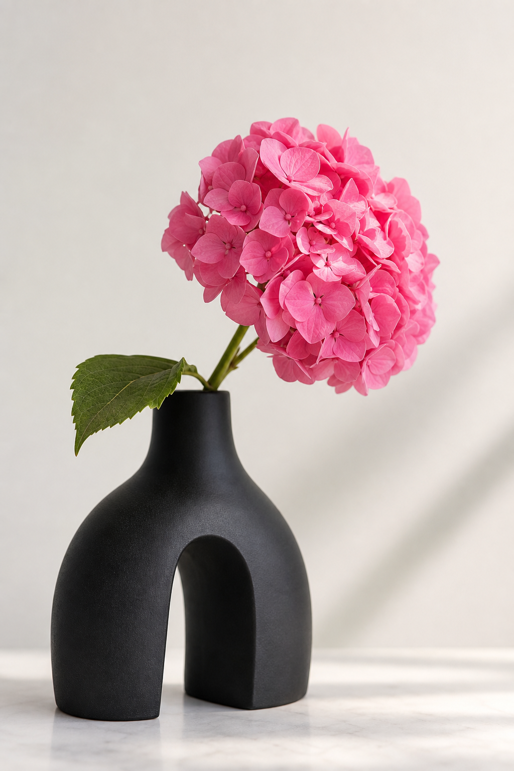 Pinke Hortensienblüte in schwarzer Designervase als Tischdeko