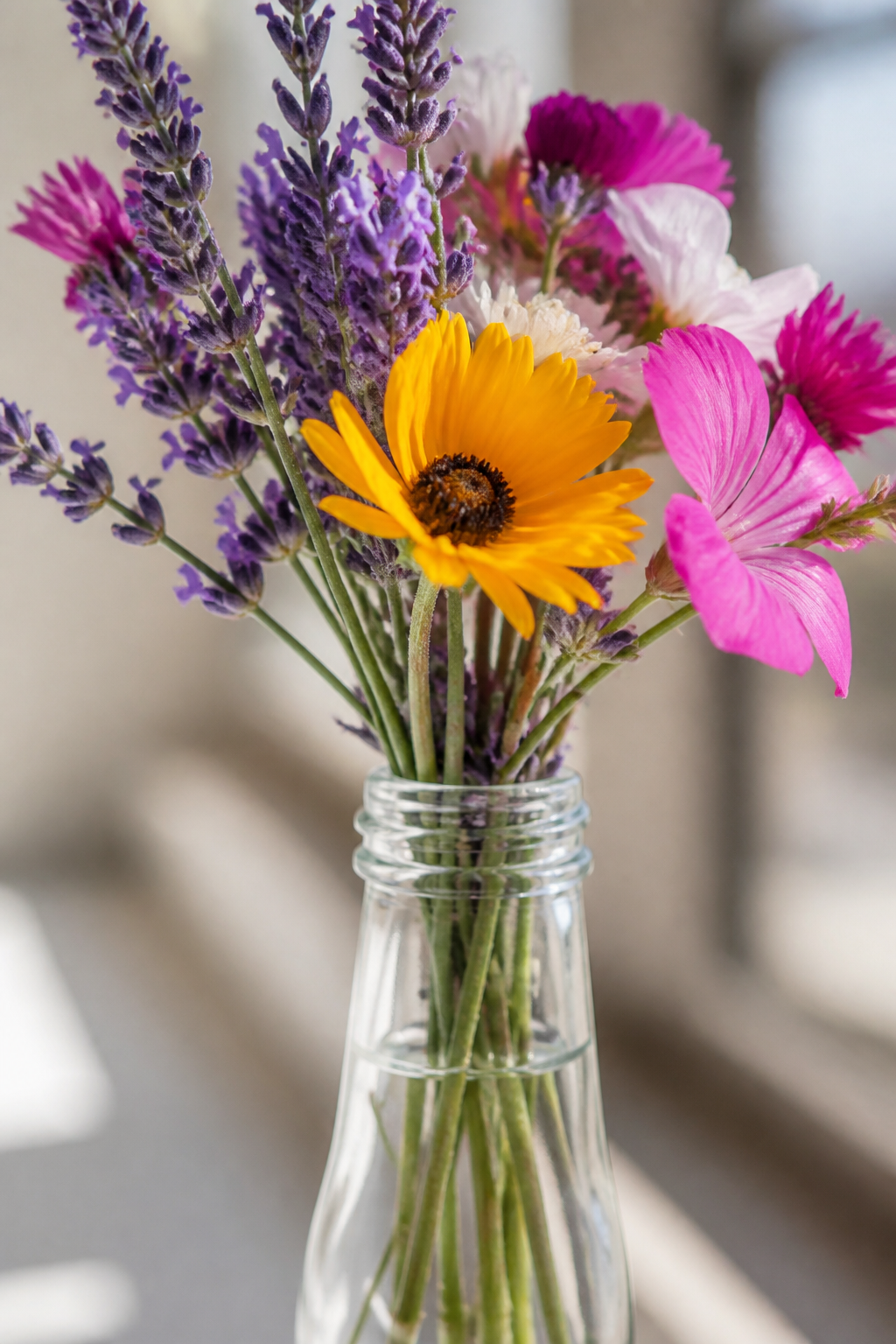 Glasflasche mit Lavendel und Sommerblumen als Tischdeko