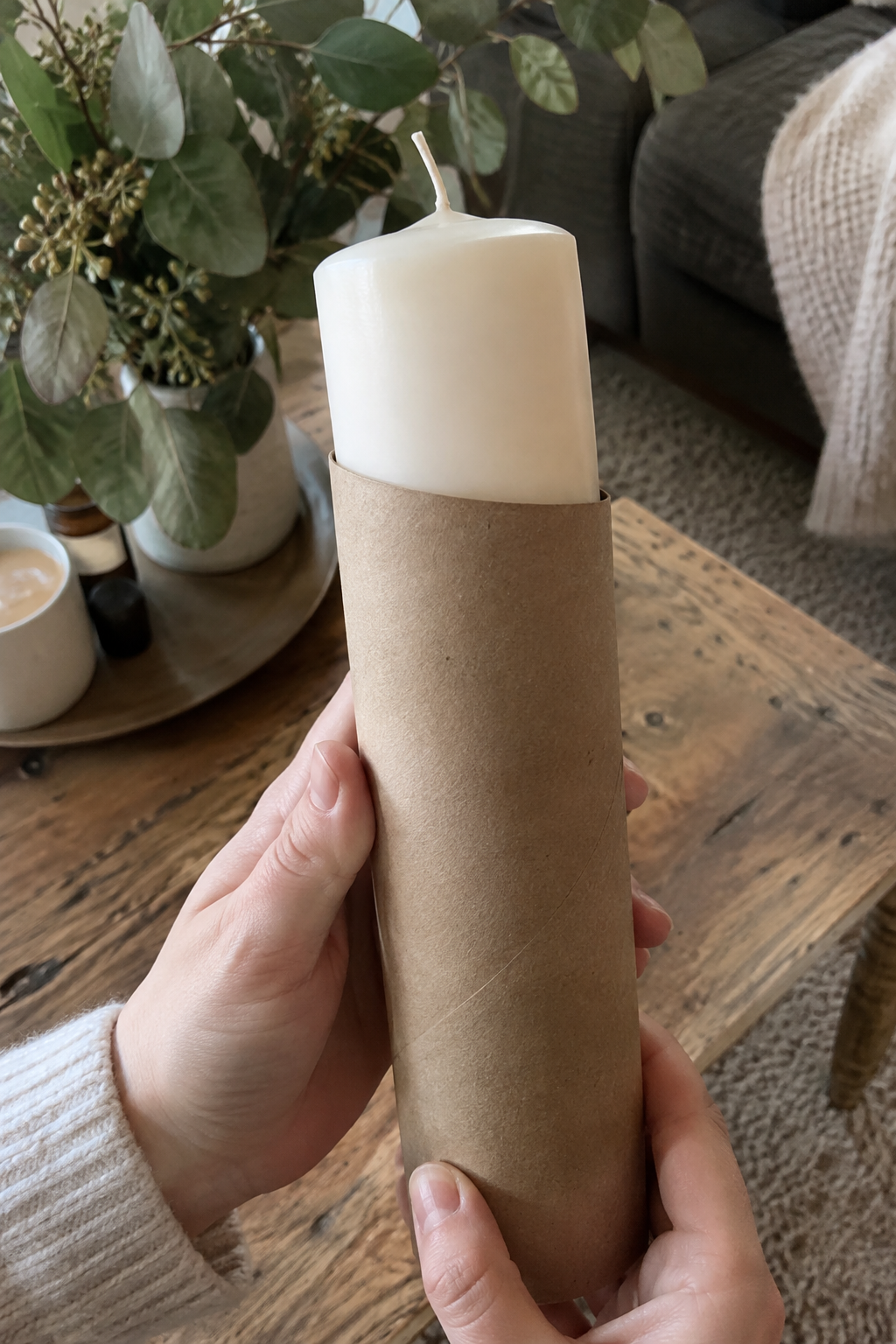 Hände halten große Kerze in schmaler Papierhülle